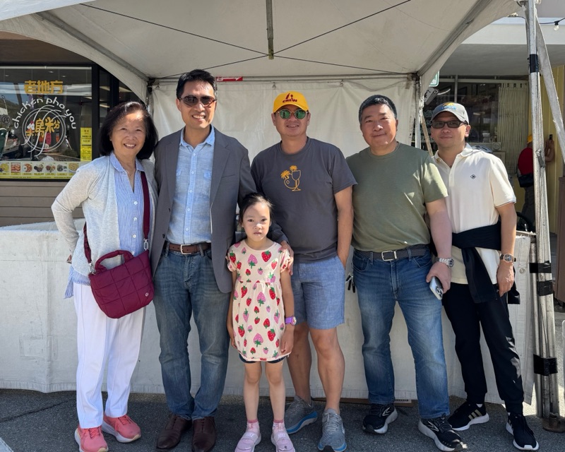 Bob Nguyen with a group of neighbors and his daughter under a tent at the Millbrae Art and Wine Festival
