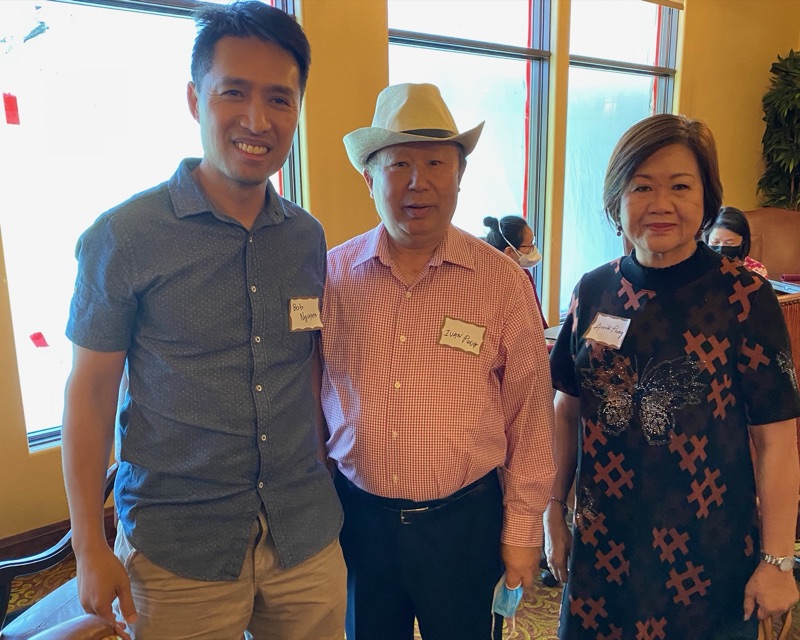 Bob Nguyen wearing a name tag with two attendees at a Millbrae community event