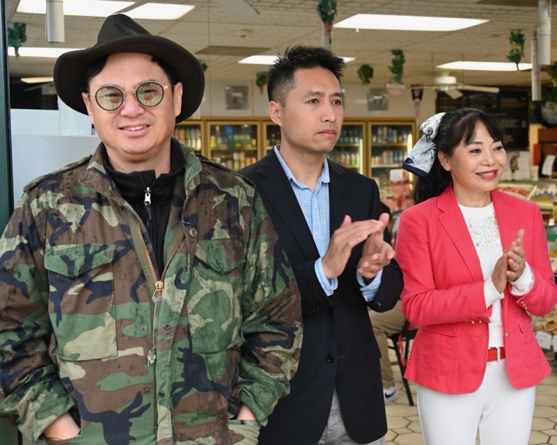 Bob Nguyen applauding at the grand opening of a Millbrae market, with two people beside him