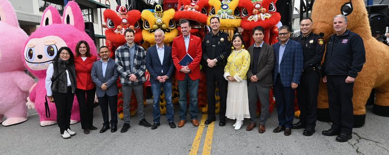 Bob Nguyen standing with Millbrae public safety officers, festival organizers and lion dancers in front of the Lunar New Year Festival stage on Broadway