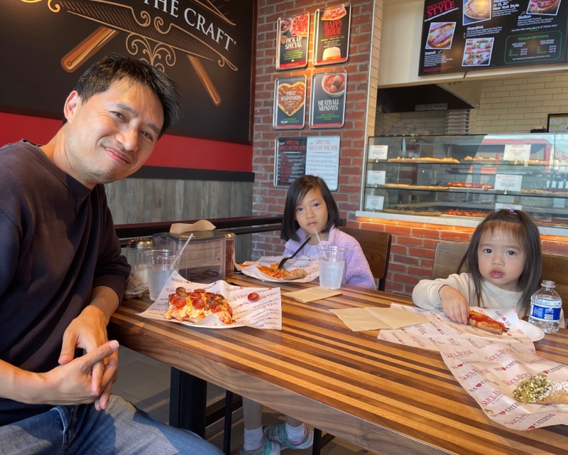 Bob Nguyen smiling at a table at Millbrae Slice House with his two daughters