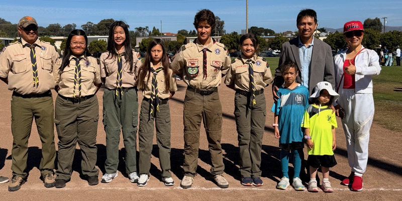Bob Nguyen and his two daughters on the field with a line of Scouts in uniform and their leader at Millbrae AYSO opening day